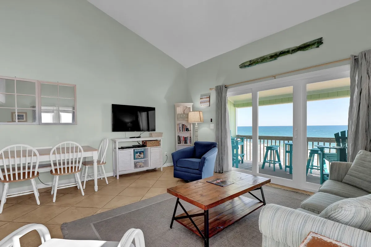 A bright, open-concept living and dining area with large windows looking out toward the ocean, comfortable seating, and a dining table—an inviting environment for social activities and relaxation.