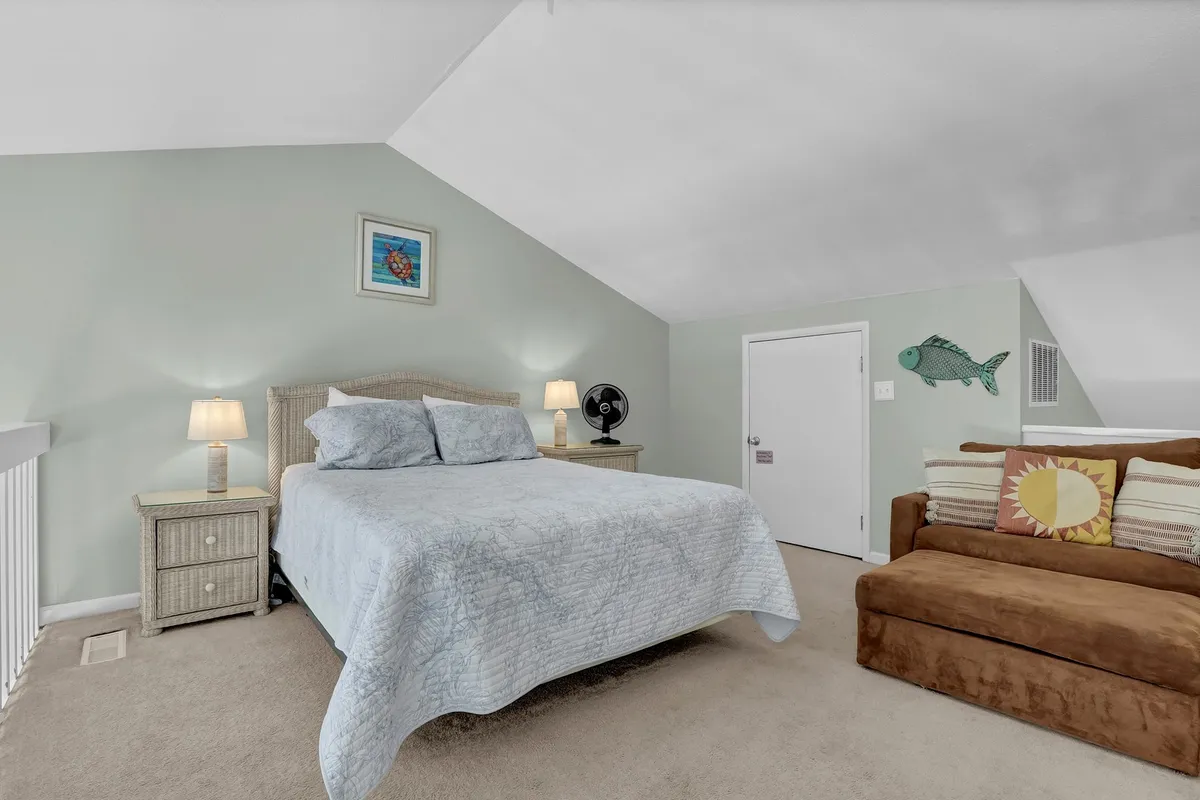 A living area that includes a comfortable sofa, a bed, modern artwork, and a lamp, creating a cozy, multi-functional space ideal for relaxing or sleeping.