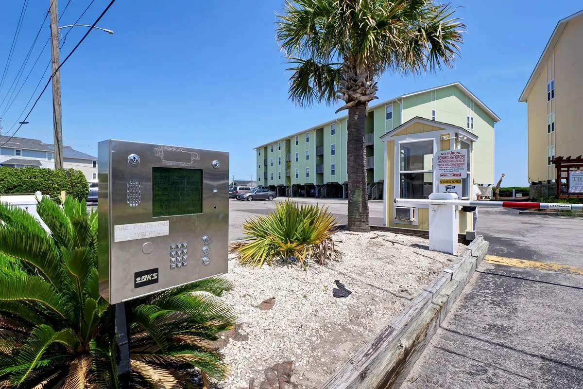 A welcoming building facade with palm trees and an intercom system, creating a sense of arrival and privacy. The exterior is clean and inviting, suggesting a peaceful, exclusive atmosphere for couples.